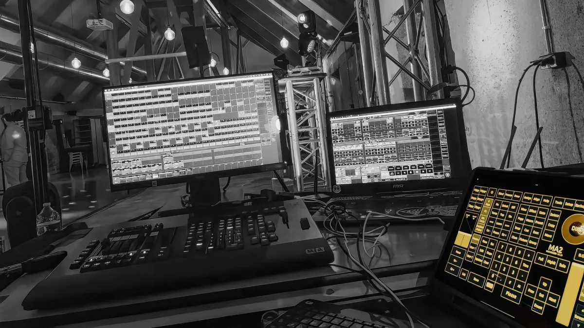 touchosc-layout-grandma2-showcase-image-01 A professional Front of House (FOH) lighting setup featuring the TouchOSC Mk2 GrandMA2 layout on a tablet alongside a physical Command Wing and multi-screen OnPC station.